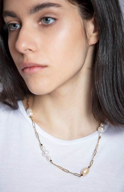 necklace is made from elongated gold-tone chain links strung with river pearls